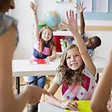 Children raising hands in classroom setting